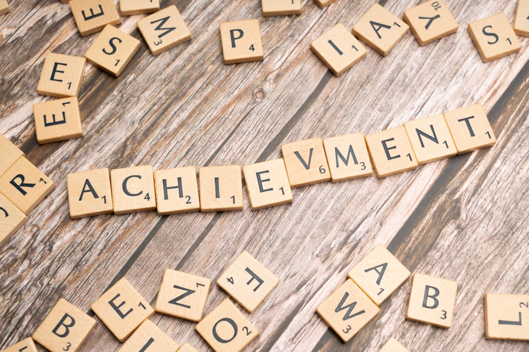 scrabble tiles spelling the word achievement on a wooden surface
