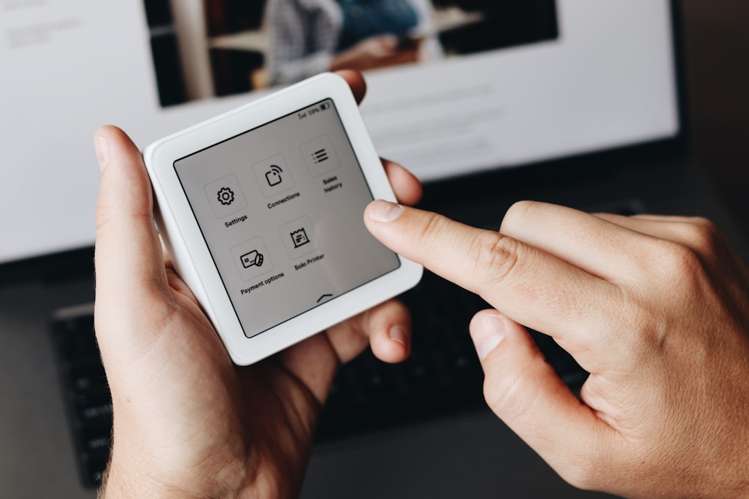 A person holding a tablet in front of a laptop
