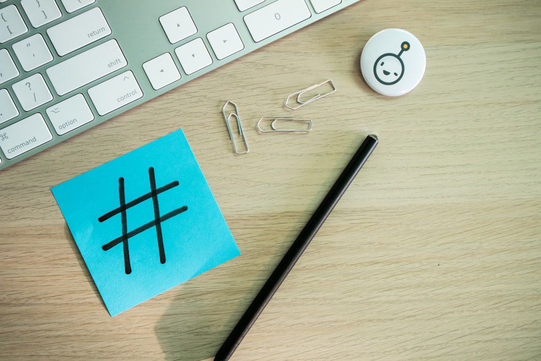a keyboard, pen, and sticky note sitting on a desk